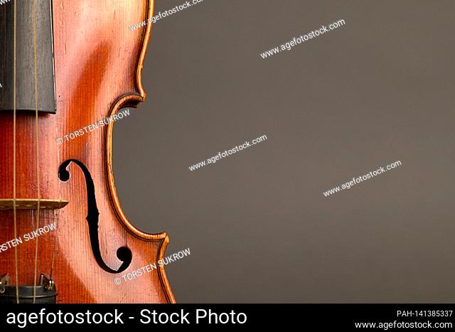 An old violin with slight scratches and damage in the bleed against a neutral, gray background with free space for text. | usage worldwide