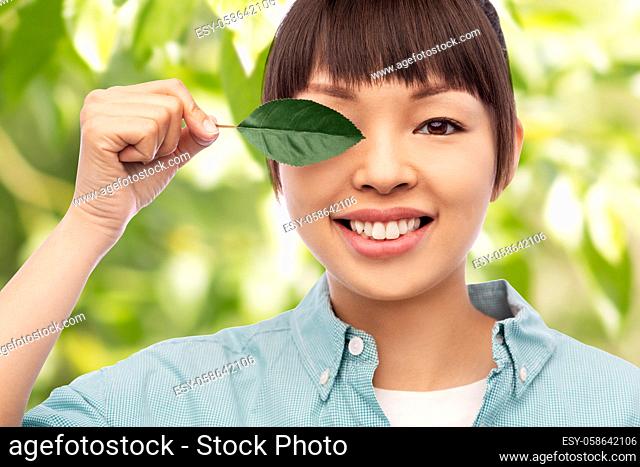 smiling asian woman holding green leaf