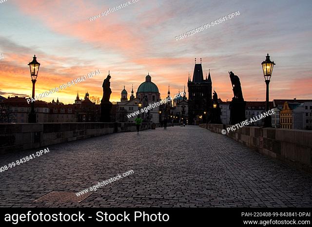 08 April 2022, Czech Republic, Prag: Vivid play of colors over the Charles Bridge. After a rainy and stormy night, the sky above the historic building shows...