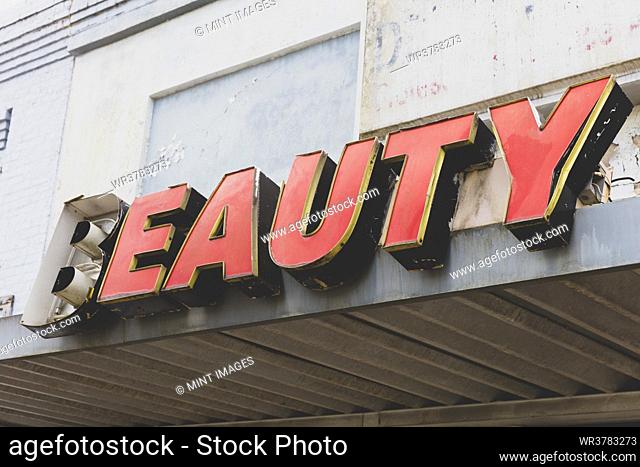 Old BEAUTY sign in front of abandoned department store, red lettering