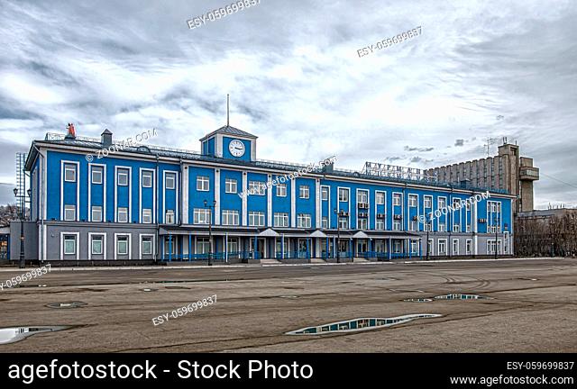 Murmansk, Russia - April 21, 2019: The main blue building of the Murmansk sea terminal. With cloudy sky and puddles near it