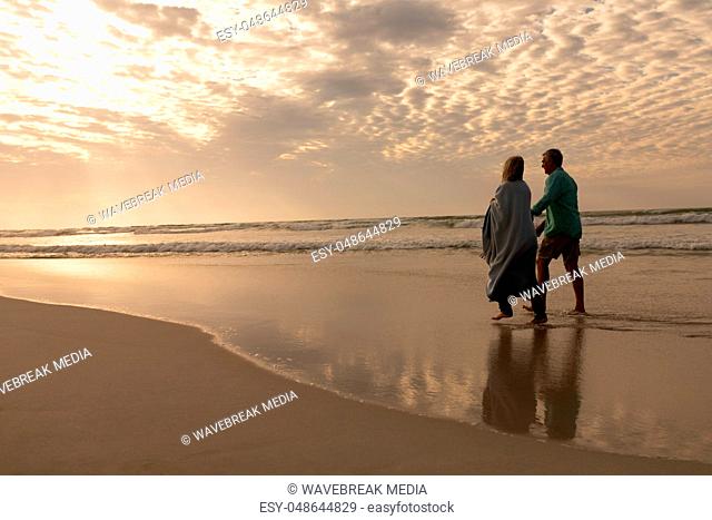 Senior couple walking hand in hand on the beach