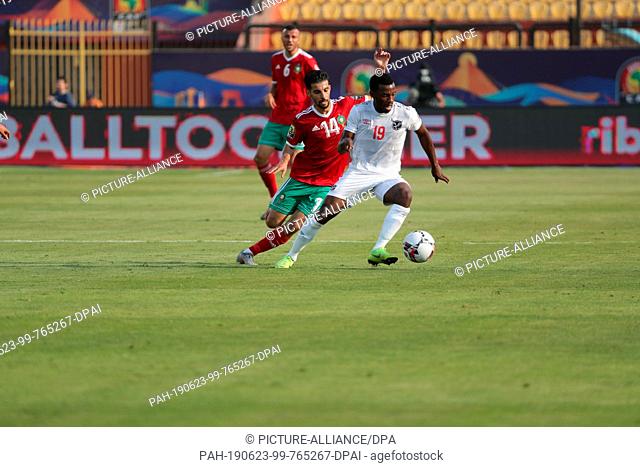 23 June 2019, Egypt, Cairo: Morocco's Mbark Boussoufa (R) and Namibia's Petrus Shitembi battle for the ball during the 2019 Africa Cup of Nations Group D soccer...