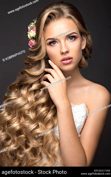 Portrait of a beautiful blond woman in the image of the bride with flowers in her hair. Picture taken in the studio on a black background