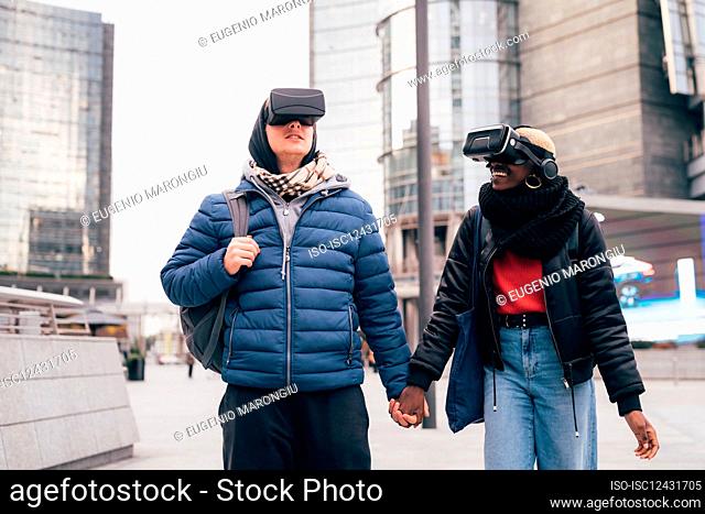 Italy, Couple withÊVRÊgoggles walking in city
