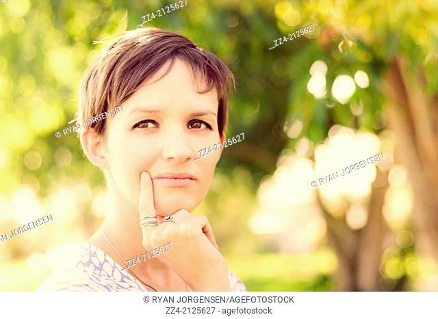 Aspirational shot of a woman with short brown hair looking out on a rural setting with visionary focus. Green ideas