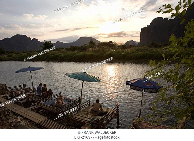 People relaxing on jetties at the river Nam Xong at sunset, Vang Vieng, Vientiane Province, Laos