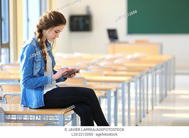 Young female student with smartphone at classroom
