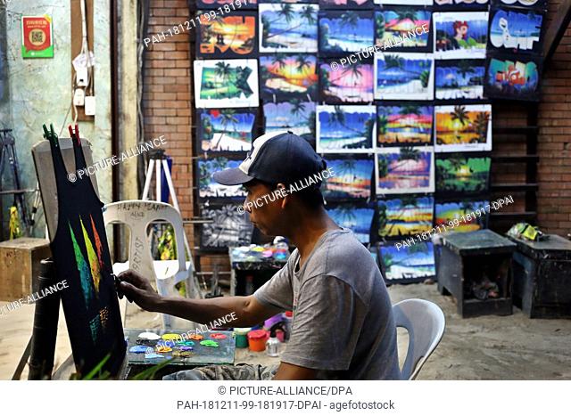 09 December 2018, Philippines, Boracay: A street artist paints T-shirts in a shop on the beach. The beaches of the island of Boracay were closed to the public...