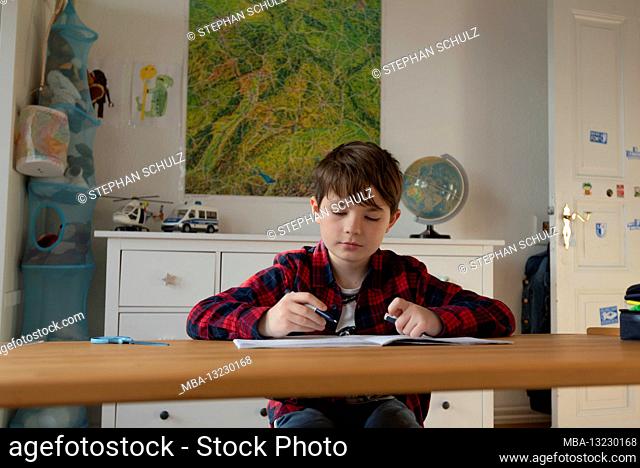 A boy sits at his desk in homeschooling doing chores for school