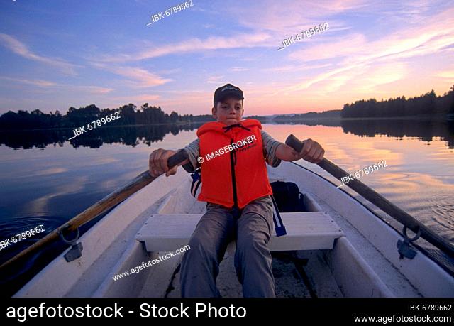 Boy in rowing boat with life jacket at sea