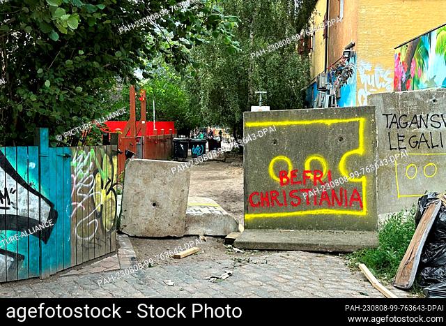 08 August 2023, Denmark, Kopenhagen: ""Befri Christiania"" (Free Christiania) is written on a blockade of a side alley of the so-called Pusher Street in the...