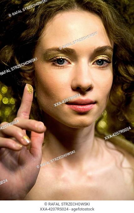 young woman wioth gloden eyeshadow on finger