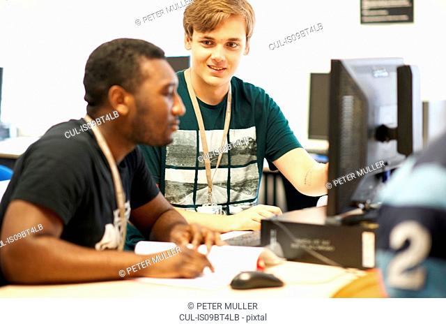 Male higher education students working at computer in college classroom