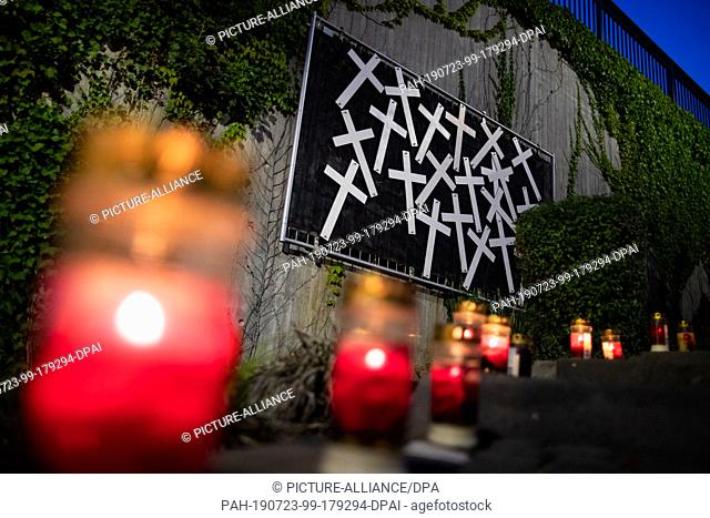 23 July 2019, North Rhine-Westphalia, Duisburg: Candles are lit at the scene of the 2010 Love Parade disaster in front of a wall of crosses to commemorate the...