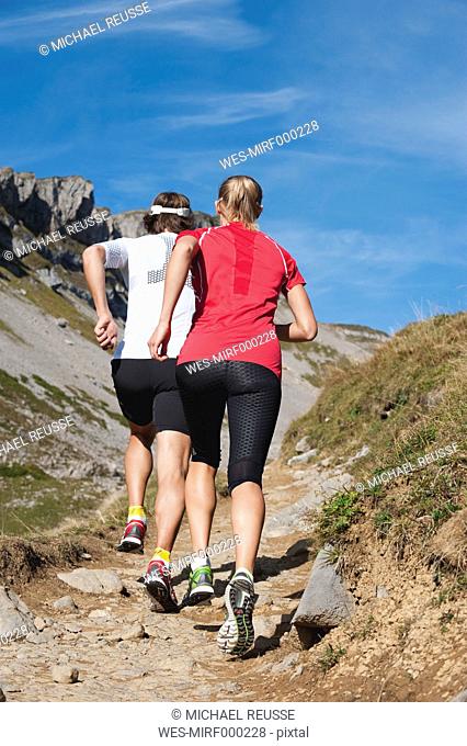 Austria, Kleinwalsertal, Man and woman running on mountain trail