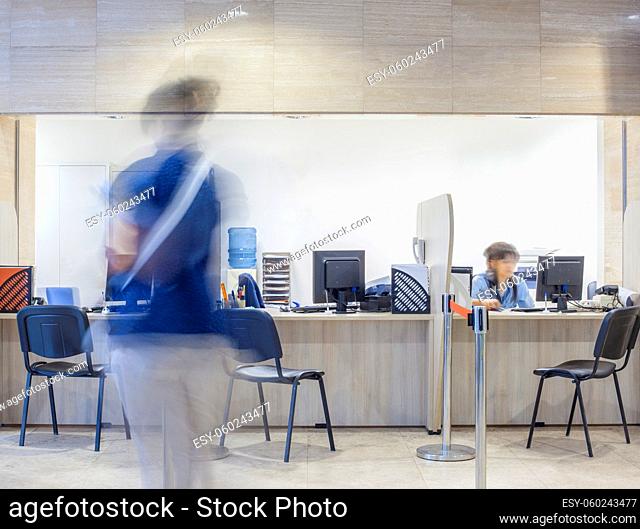 Three seats in front of a Bank, customs, office, hospital, etc. registration desk with blurred figures of a clerk and a customer