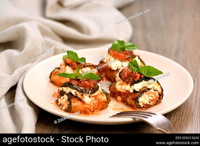 Baked zucchini rolls stuffed with ricotta and basil under tomato-onion-carrot gravy