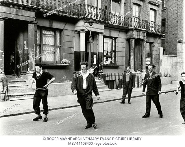 Young men playing some kind of ball game in the roadway, Southam Street, North Kensington, West London
