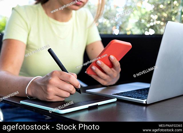 Woman with digitized pen writing in graphic tablet