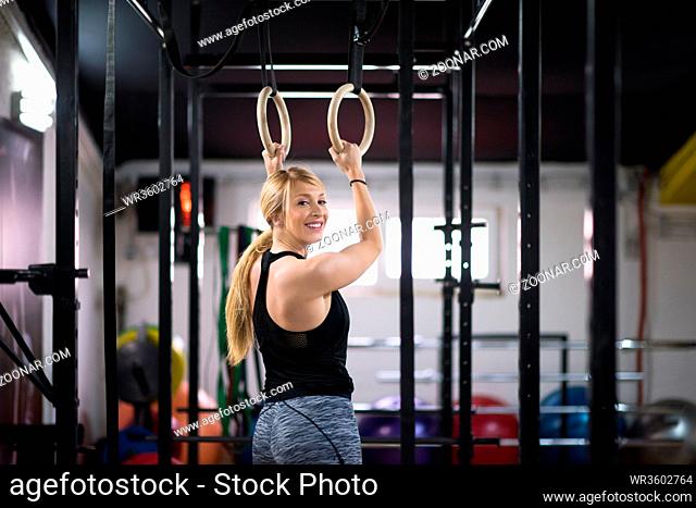 young athletic woman working out on gymnastic rings at the cross fitness gym