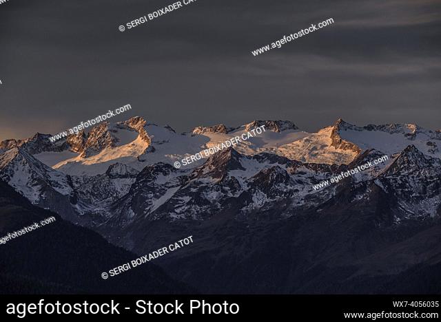 Reddish sunrise over the snowy Maladetas massif and the Aneto peak. Seen from the Varradòs Valley in autumn (Aran Valley, Catalonia, Spain)