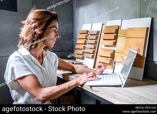 Woman working on laptop with wood tiles on desk at office