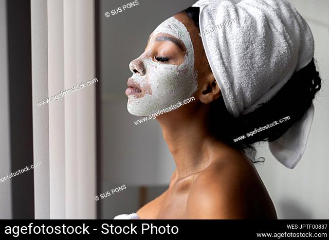 Woman with eyes closed wearing towel on head at home