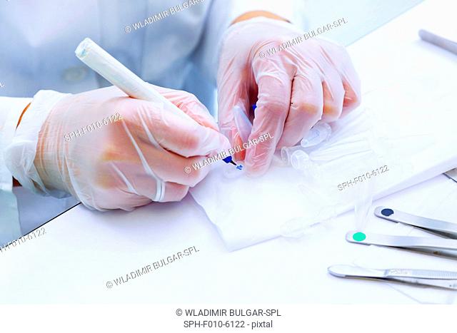 Laboratory technician writing on test tube