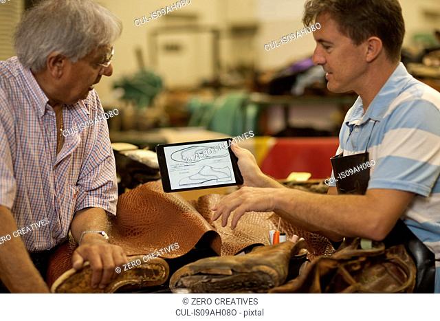 Cobbler and apprentice holding digital tablet