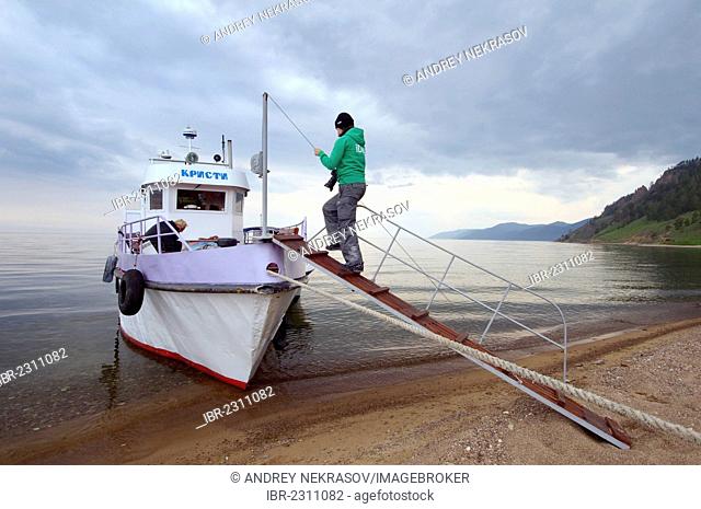 Passenger entering boat, Bolshiye Koty, shore of Lake Baikal, Irkutsk region, Siberia, Russian Federation, Eurasia
