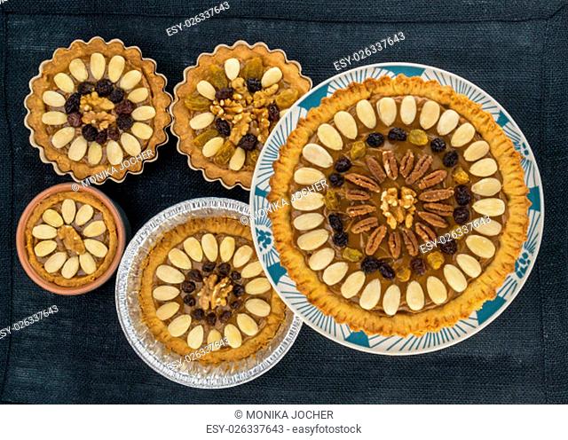 Five round traditional Polish Easter cakes ""Mazurek"" with almonds, raisins and walnuts on the dark fabric background