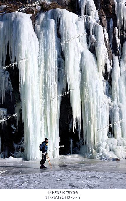 Man standing in front of frozen waterfall