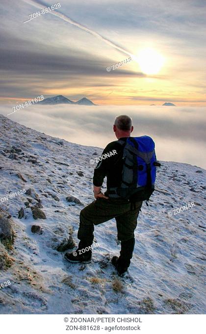 Hiker on Ben Challum looking across a cloud inversion to Ben More and Stob Binnein
