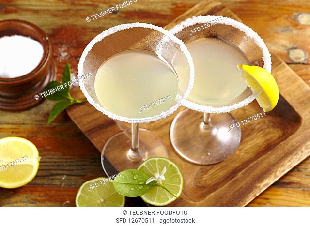 Two glasses of margarita with salted rims, tequila, orange liqueur and lemon