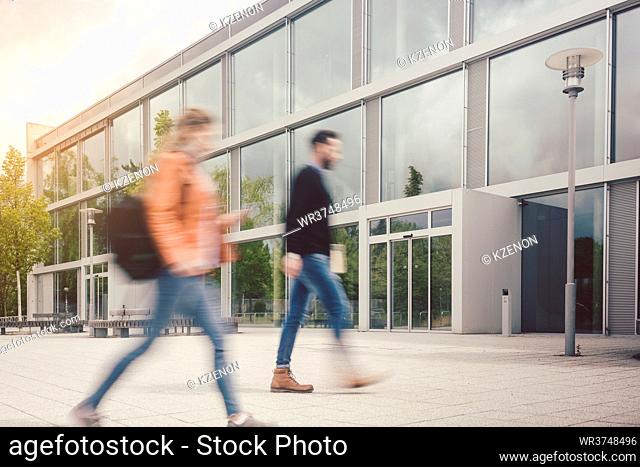 Blurred silhouette of students being busy on university campus in front of main building