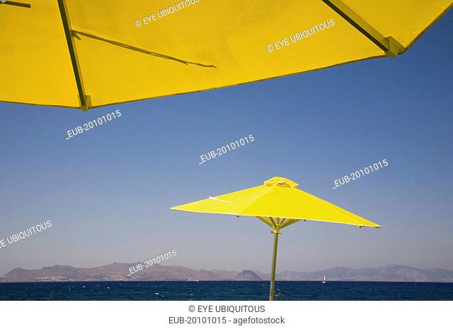 Bright yellow parasols on beach outside Kos Town with view towards distant coastline beyond