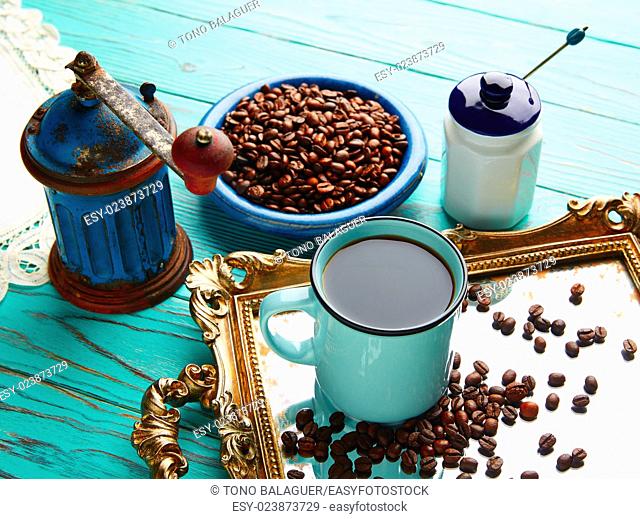 Coffee cup with vintage grinder on wooden old table and golden tray beans