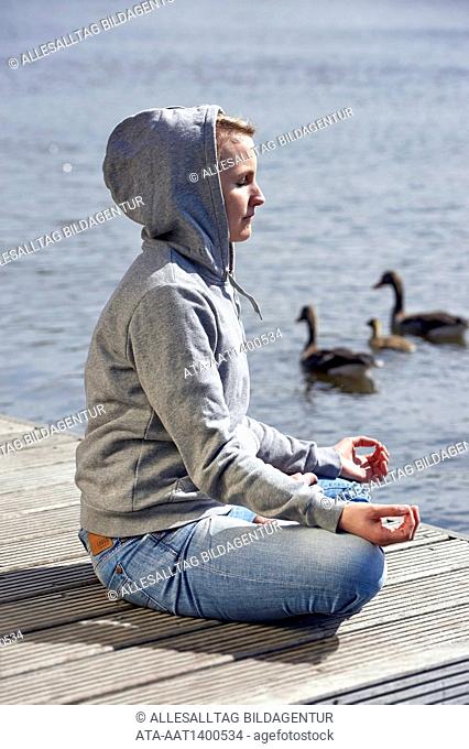 Woman making yoga on a landing stage