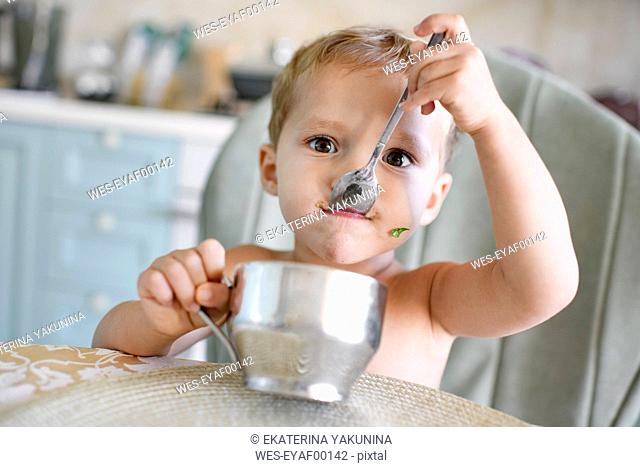 Portrait of little girl eating from metal mug