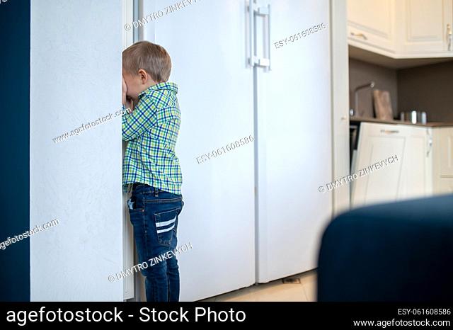 Blond kid standing in the corner and covering his face with hands during the game