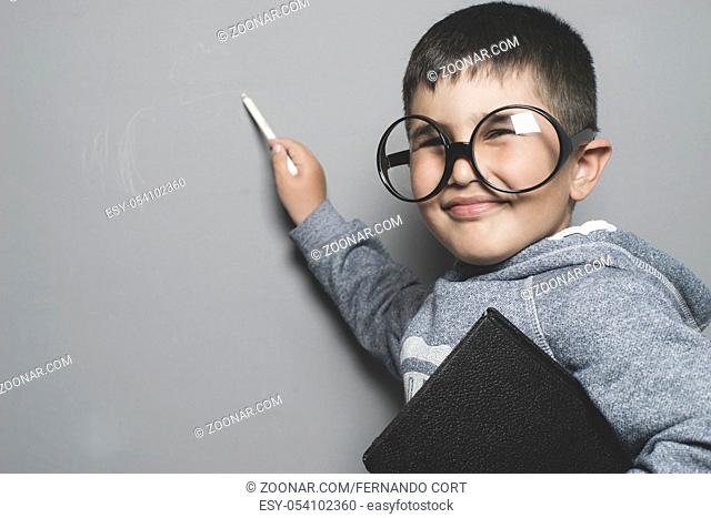 schoolboy, young student writing on a blackboard school with a book in hand and big glasses