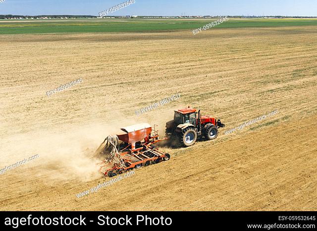 Aerial View. Tractor With Seed Drill Machine Sowing The Seeds For Crops In Spring Season. Beginning Of Agricultural Spring Season