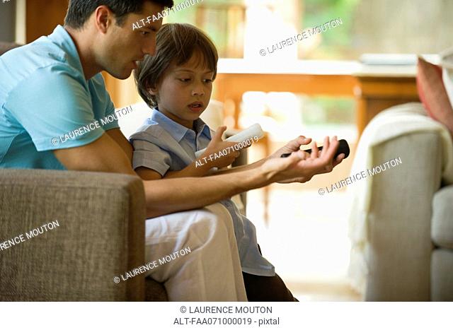 Father and son playing video game using wireless controllers