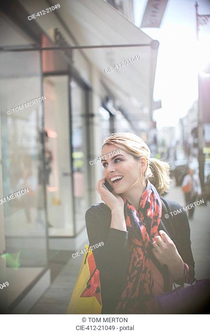 Woman talking on cell phone while walking down city street