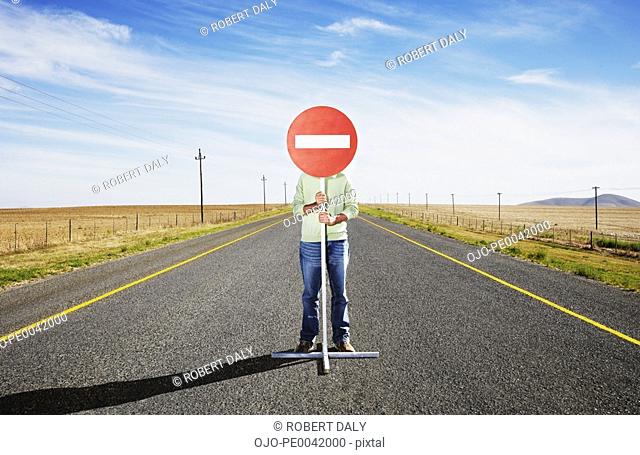 A man holding a sign in the middle of the road