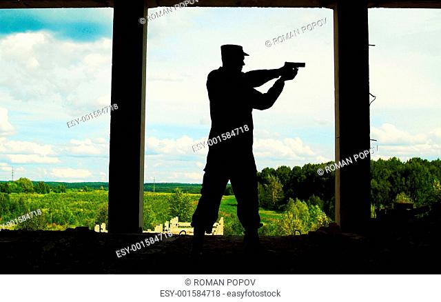 The Contour of soldier with a gun opposite to window with peace landscape