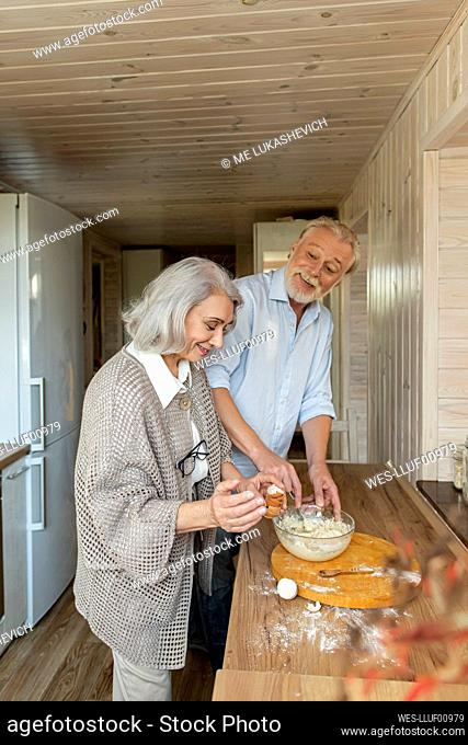 Senior couple preparing dough for bread in kitchen