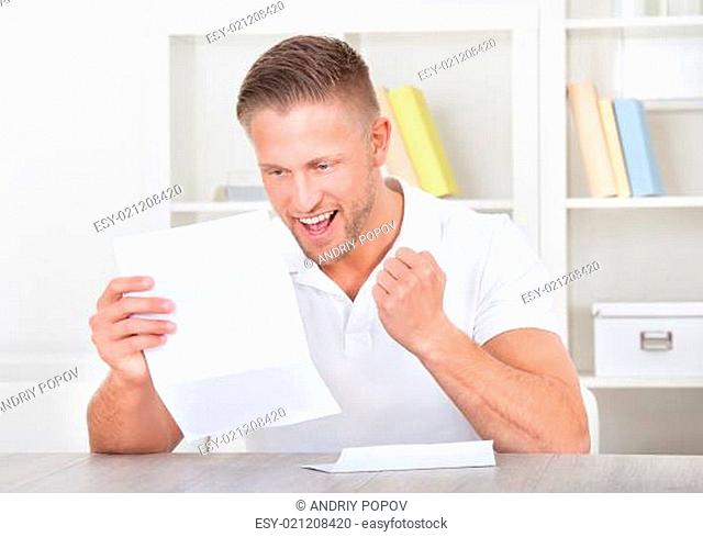 Man cheering in jubilation as he reads a letter