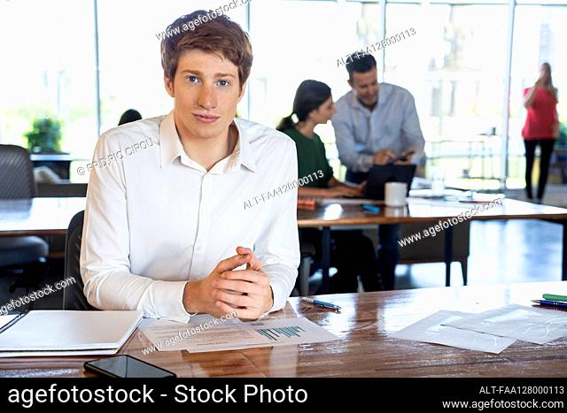 Portrait of young man sitting at desk in office